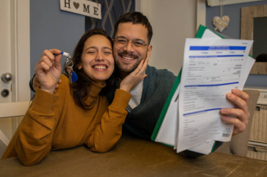 Happy couple holding house keys and paperwork, symbolizing tenancy by the entirety.